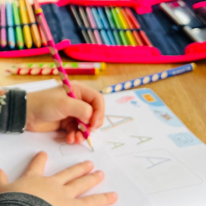 Lernen und Hausaufgaben Kinderhände bearbeiten ein Arbeitsblatt am Tisch.